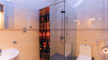 Une salle de bain avec une douche à parois de verre, des toilettes et un lavabo.