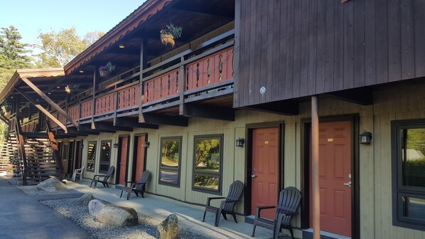 A rustic lodge with a wooden exterior, multiple windows, and a porch area with Adirondack chairs. - Timber Inn Motel (Ludlow)