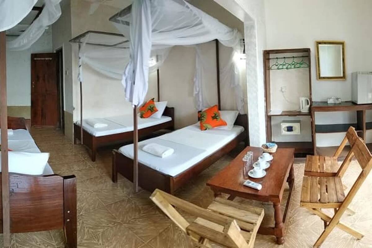 Una habitación con cuatro camas, cada una con dosel, una mesa de madera y una silla.