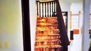 A staircase with a wooden handrail and a dark-colored carpet. - Casa Arin (Mazatlán)