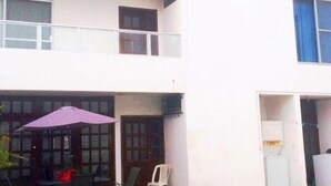 A two-story building with a balcony on the upper floor and a covered outdoor seating area with chairs and a table. - Casa Arin (Mazatlán)