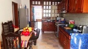 A kitchen with wooden cabinets, a marble countertop, and a dining area with a table and chairs. - Casa Arin (Mazatlán)