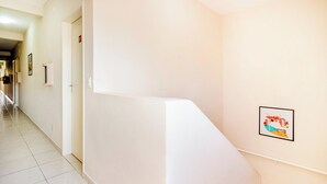 A clean, well-lit hallway with a white wall and a framed picture. - OYO Hotel Itarantim, São Paulo (São Paulo)