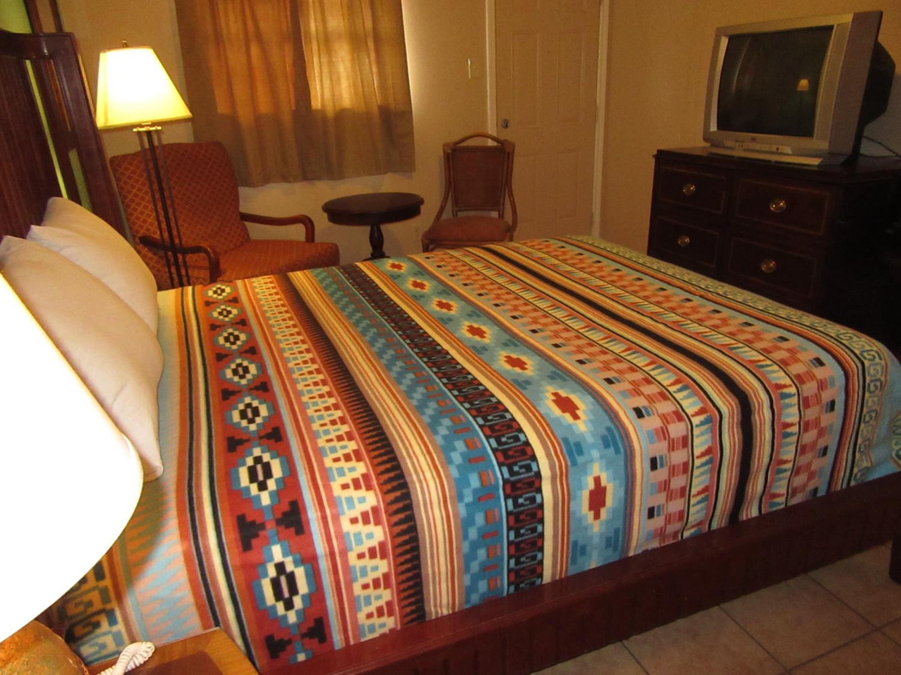 Une chambre d’hôtel avec un grand lit, une télévision, un bureau et une chaise.