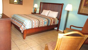 Un dormitorio con cama, dos lámparas de noche, una silla, cómoda y un espejo en la pared.