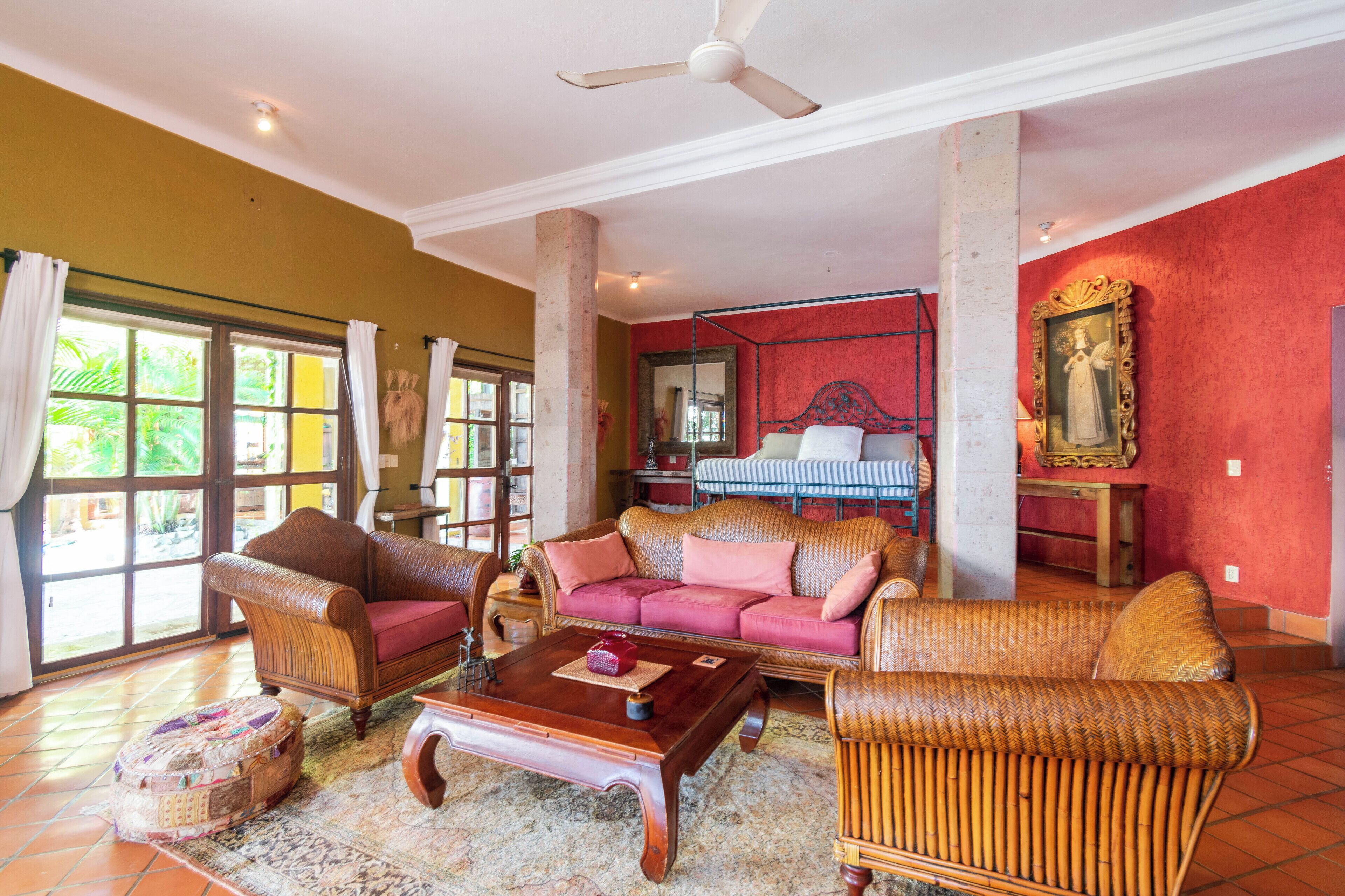 A spacious living room with a large window, a ceiling fan, and a piano in the background.
