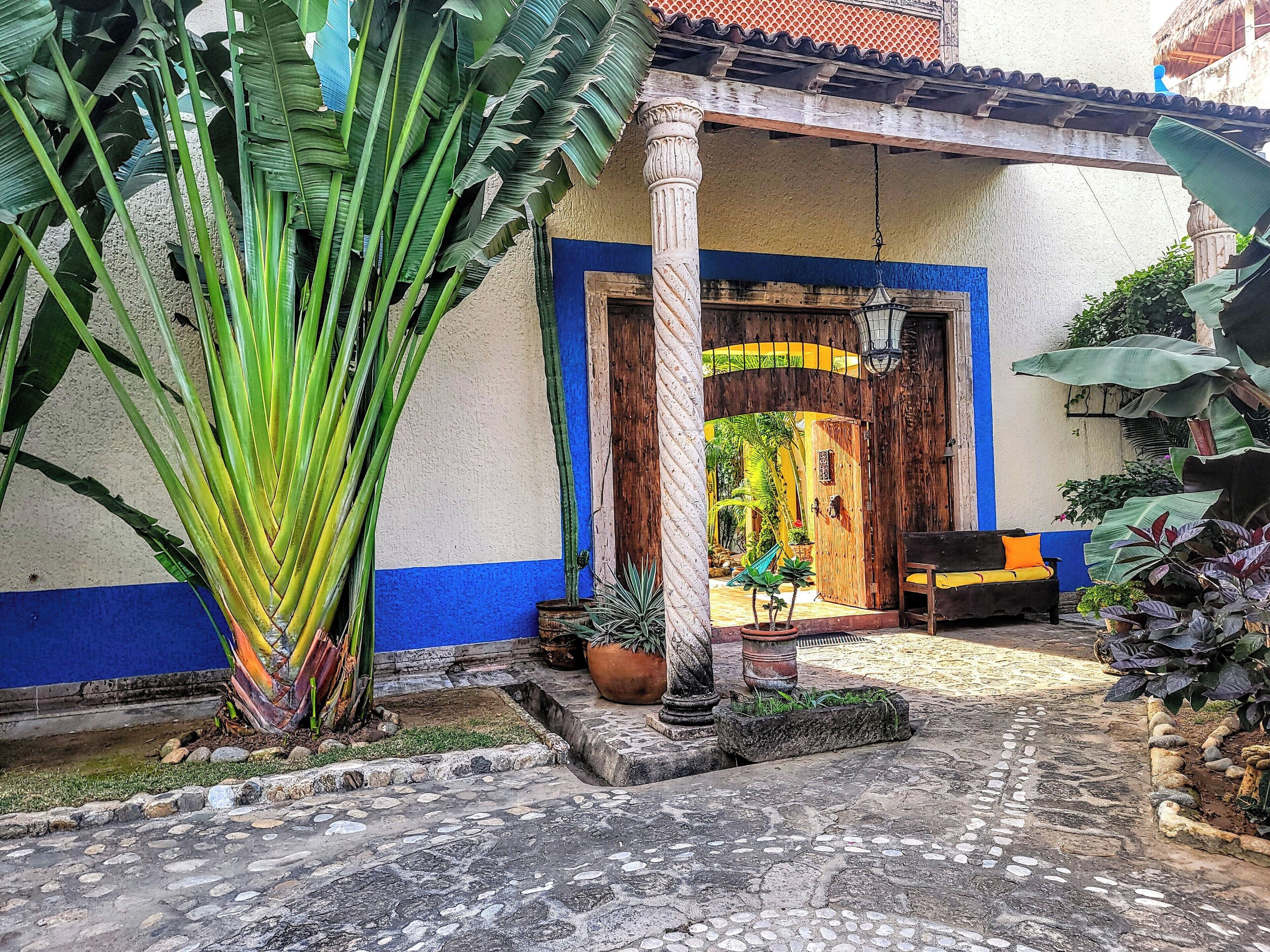 A courtyard with a stone floor, a wooden door, and a bench.