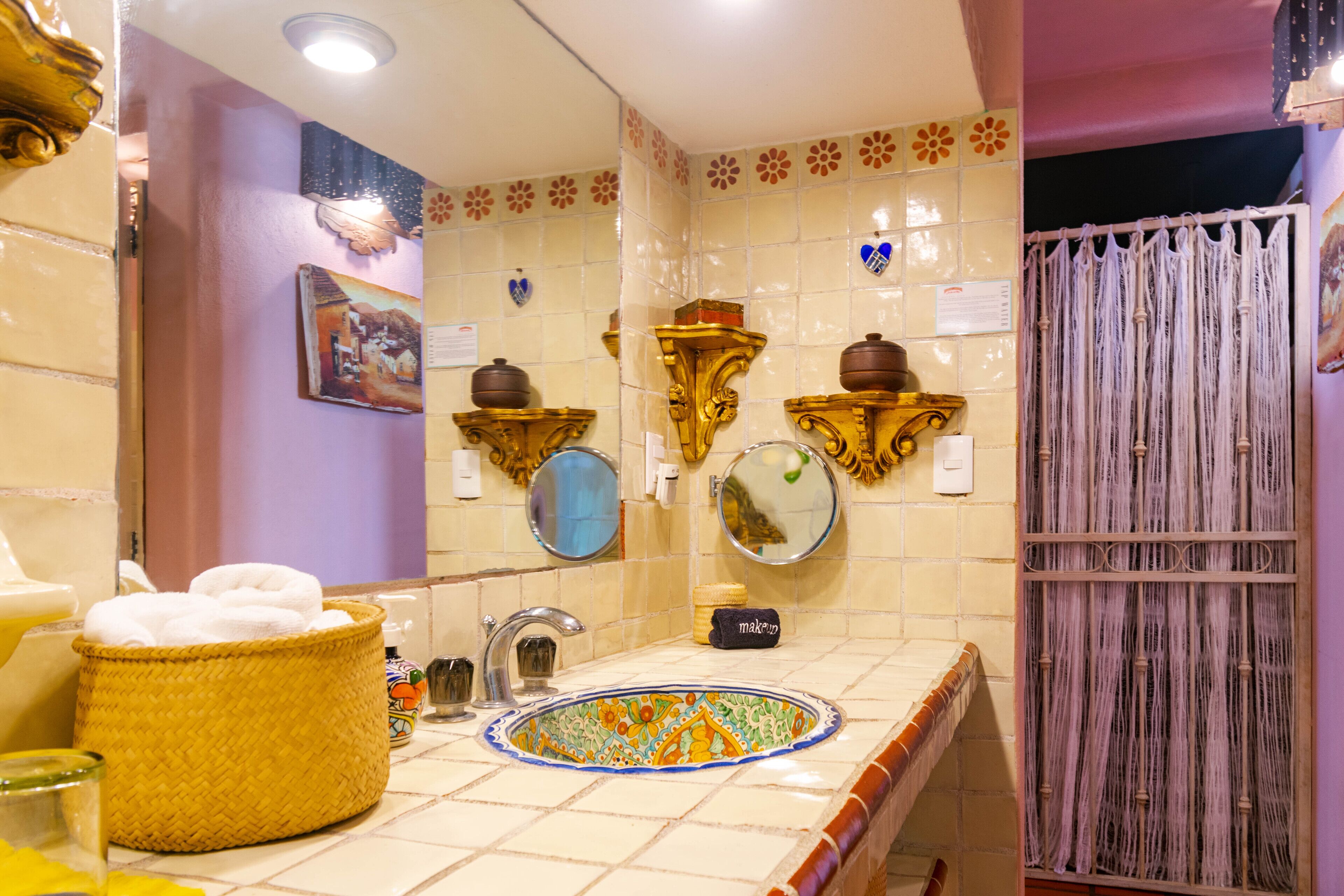 Une salle de bain avec un lavabo décoratif, un panier tressé jaune et un miroir.