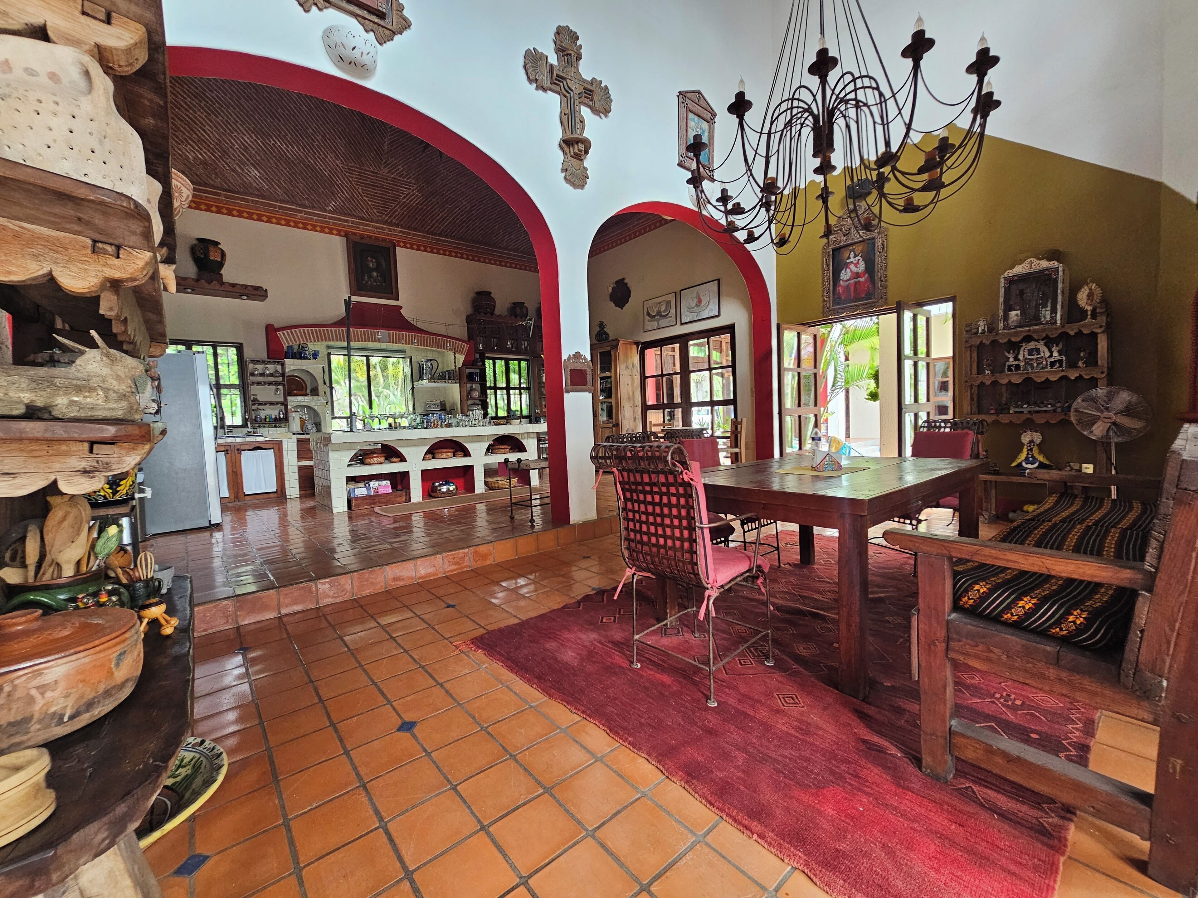 Une cuisine spacieuse avec un coin repas, décorée dans des tons de rouge et de blanc, dotée de meubles en bois et d’un sol carrelé.