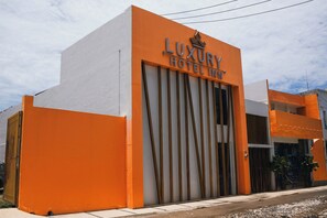 A modern building with a prominent orange facade and a sign that reads "Luxury Hotel Inn." - Luxury Hotel Inn (La Penita de Jaltemba)