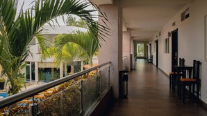 Um corredor com corrimão, uma lixeira e uma área de estar com cadeiras.