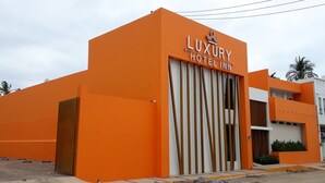 Um edifício moderno com fachada laranja chamativa e um letreiro que diz "LUXURY HOTEL INN".