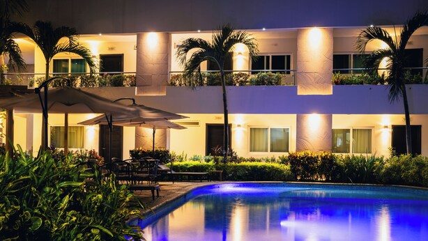Um hotel moderno com piscina, área de estar externa e varandas bem iluminadas.