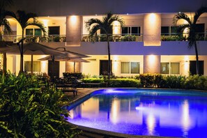 A modern hotel with a swimming pool, outdoor seating, and well-lit balconies. - Luxury Hotel Inn (La Penita de Jaltemba)