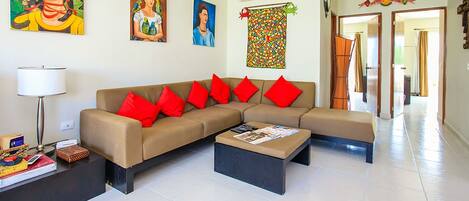 A living room with a beige sectional sofa, red cushions, a black coffee table, and a floor lamp.