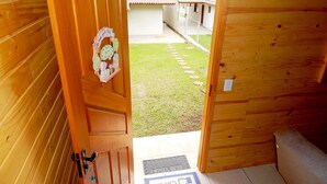 Uma porta de madeira dá para uma pequena área externa com chão de azulejos e um tapete de boas-vindas.