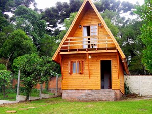 A wooden cabin with a triangular roof, a front door, and a small porch. - Cabana da Serra Gaucha (Canela)