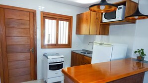 A kitchen with wooden cabinets, a gas stove, a microwave, and a refrigerator. - Residencial de Luxe Ouro 01 (Canela)