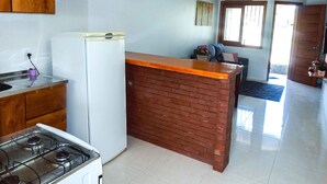 A kitchen with a stove, microwave, and hanging pendant lights. - Residencial de Luxe Ouro 01 (Canela)
