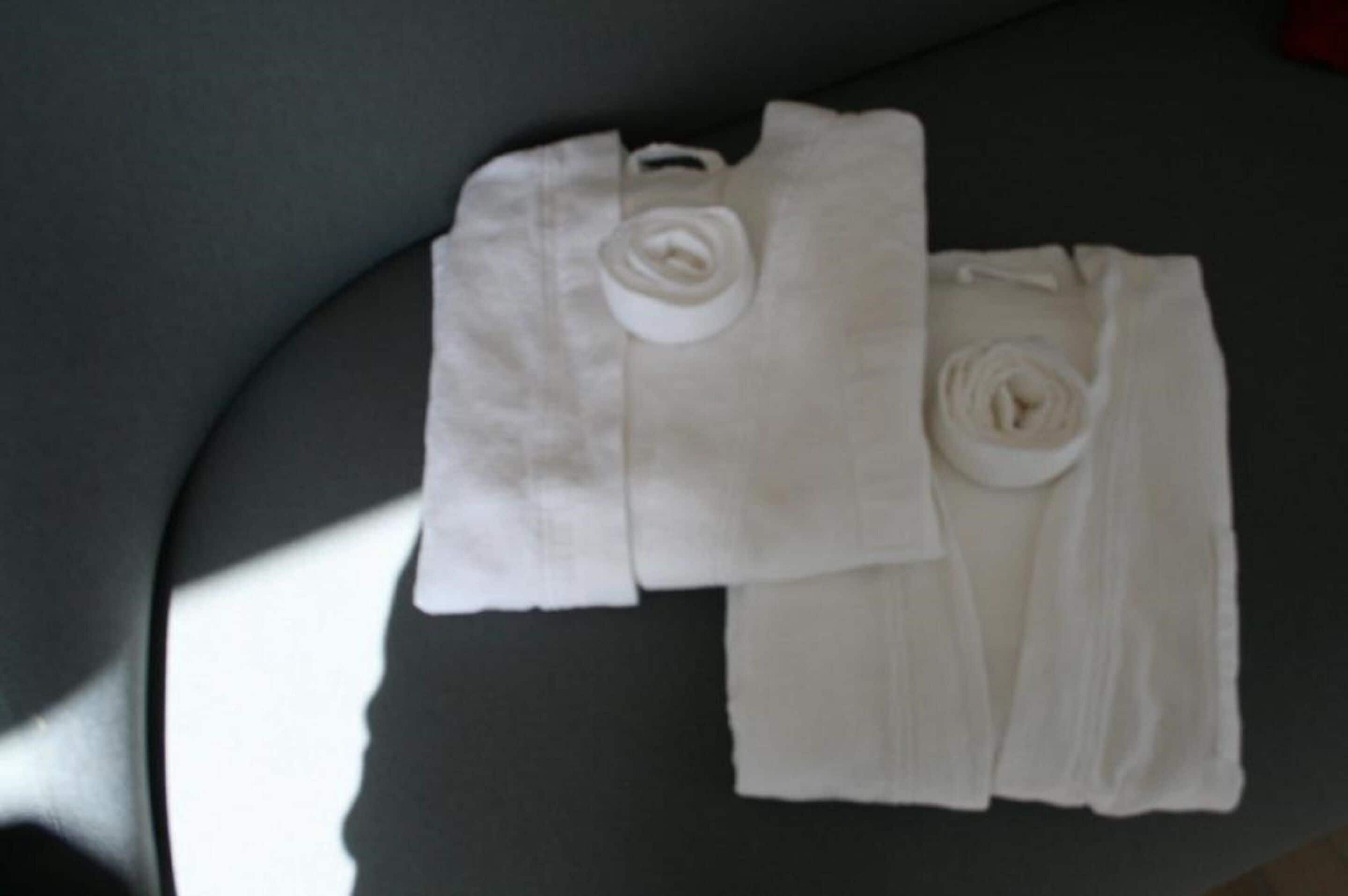 A neatly folded white towel and a rolled white towel on a dark surface.