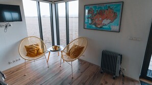 Una habitación con un ventanal grande, un mapa de Islandia, una silla, una mesa y un radiador.