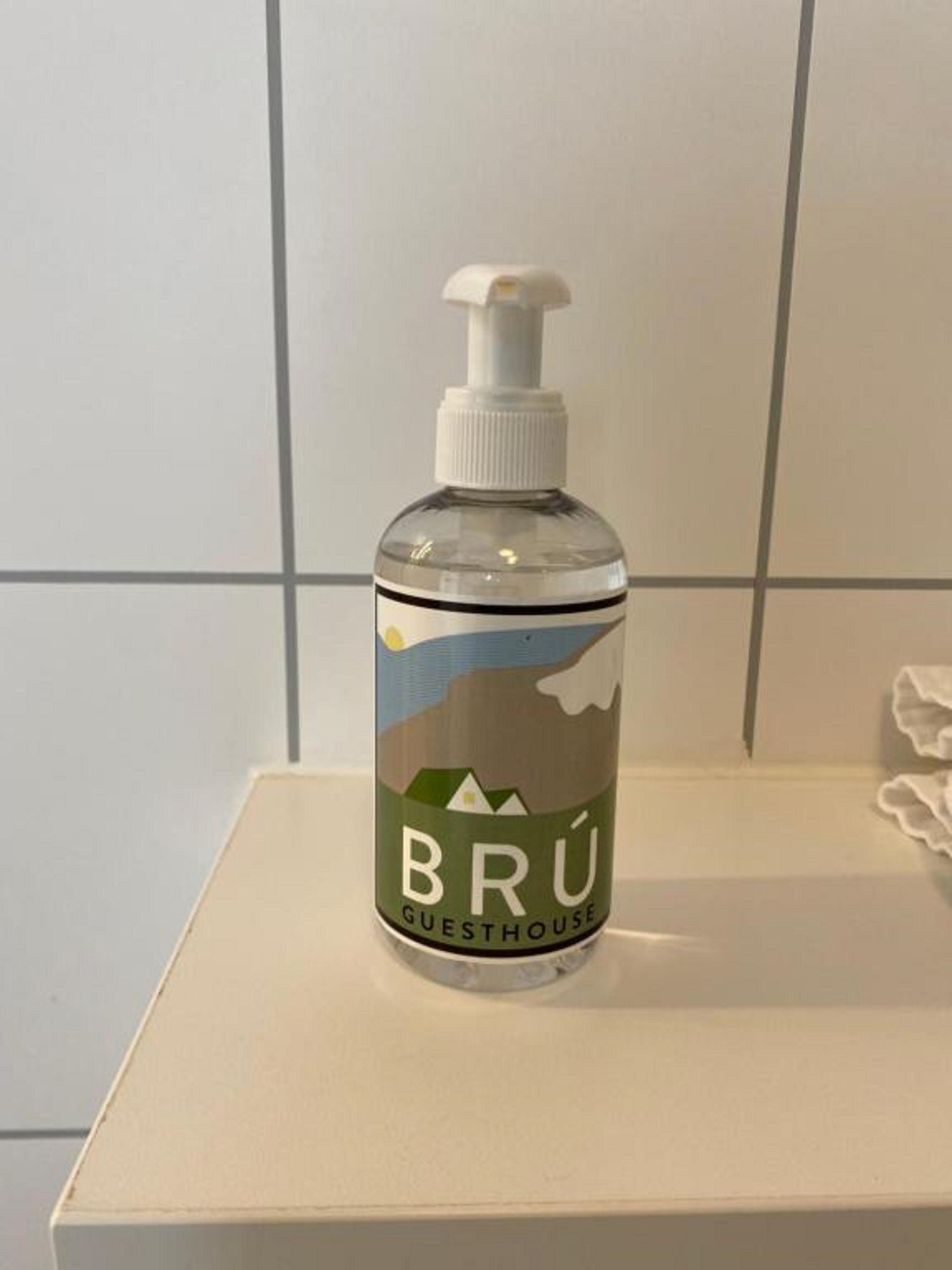 A bottle of Brú Guesthouse hand sanitizer on a white surface.