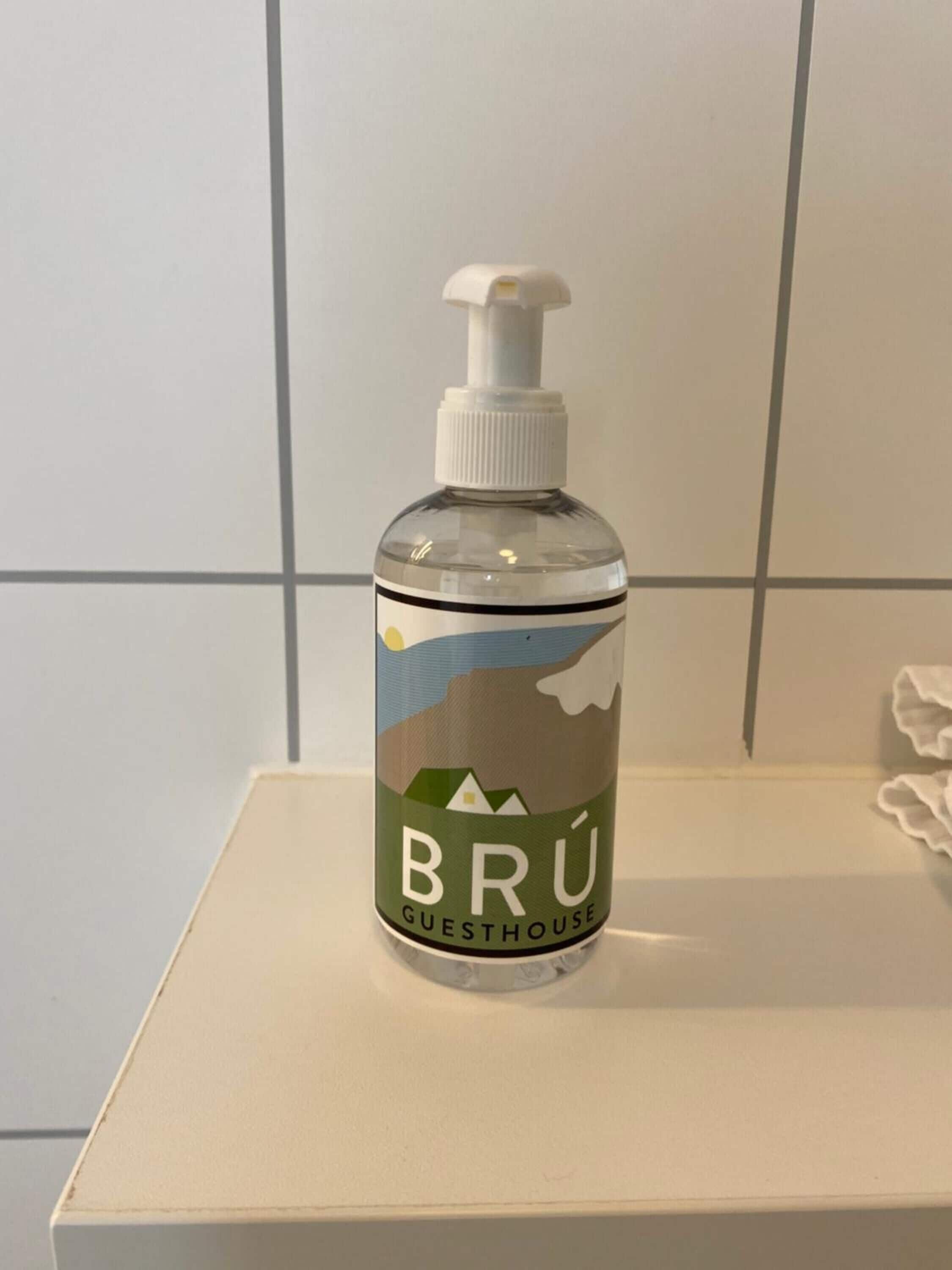 A bottle of Brú Guesthouse hand sanitizer on a white surface.