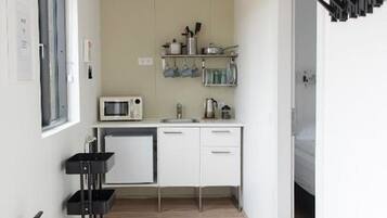 A compact kitchen with white cabinets, a microwave, and a small countertop. A fire extinguisher is mounted on the wall.
