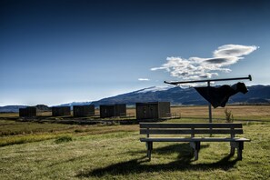 A bench in a grassy field with a backdrop of mountains and a clear sky.