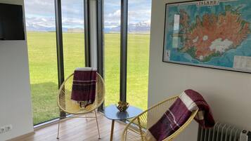 A room with large windows, two wicker chairs, a small table, and a map on the wall.