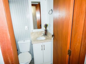 A bathroom with a white toilet, a sink with a marble countertop, and a wooden door. - Apartamento Villagio di Maggi Condominio (Canela)