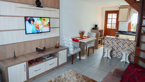 Una sala de estar moderna con un televisor de pantalla plana, un comedor y una cocina.