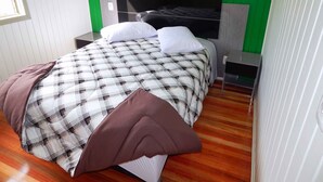 Un dormitorio moderno con una cama grande, una pared de acento verde y suelo de madera.