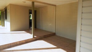 Amplia habitación con techo alto y ventana grande que deja entrar luz natural. El piso está cubierto de baldosas y se observa una puerta que da a otra zona.