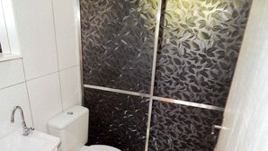 A small bathroom with a toilet, sink, and cabinet. - Chales da Serra Gaucha 02 (Gramado)