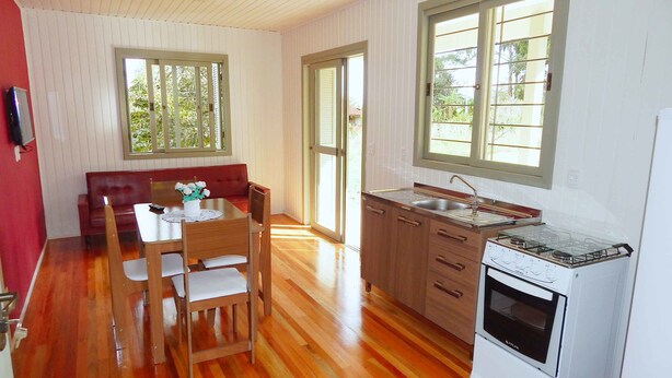 A compact kitchen with wooden cabinets, a gas stove, and a sink. - Chales da Serra Gaucha 02 (Gramado)