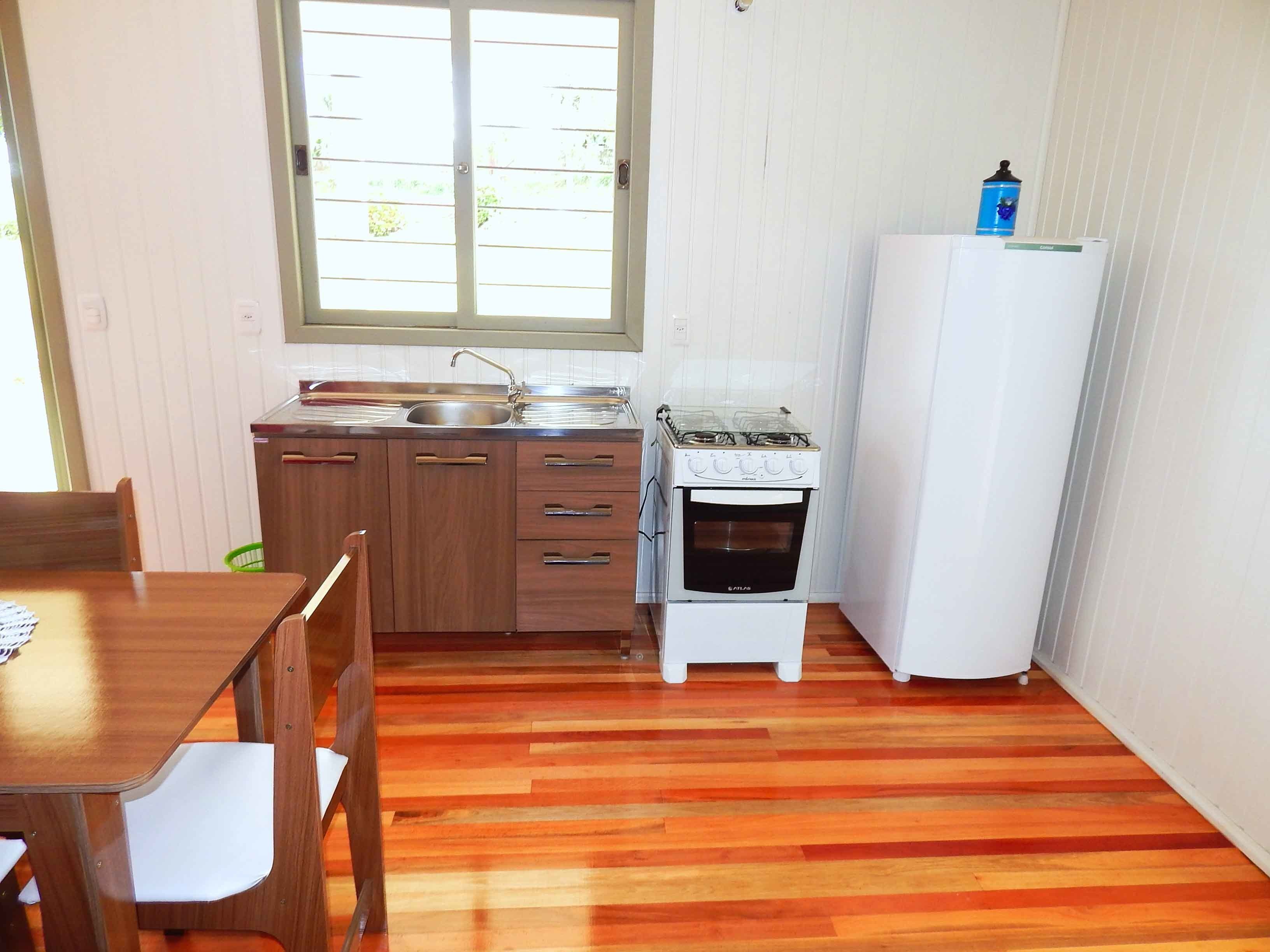 Una cocina pequeña con armarios de madera, un fregadero, una estufa y un refrigerador.