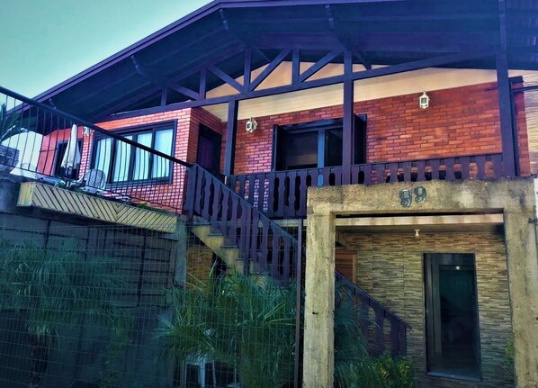 A two-story building with a red brick facade, a wooden staircase, and a balcony. - Apartamentos Gramado House (Gramado)