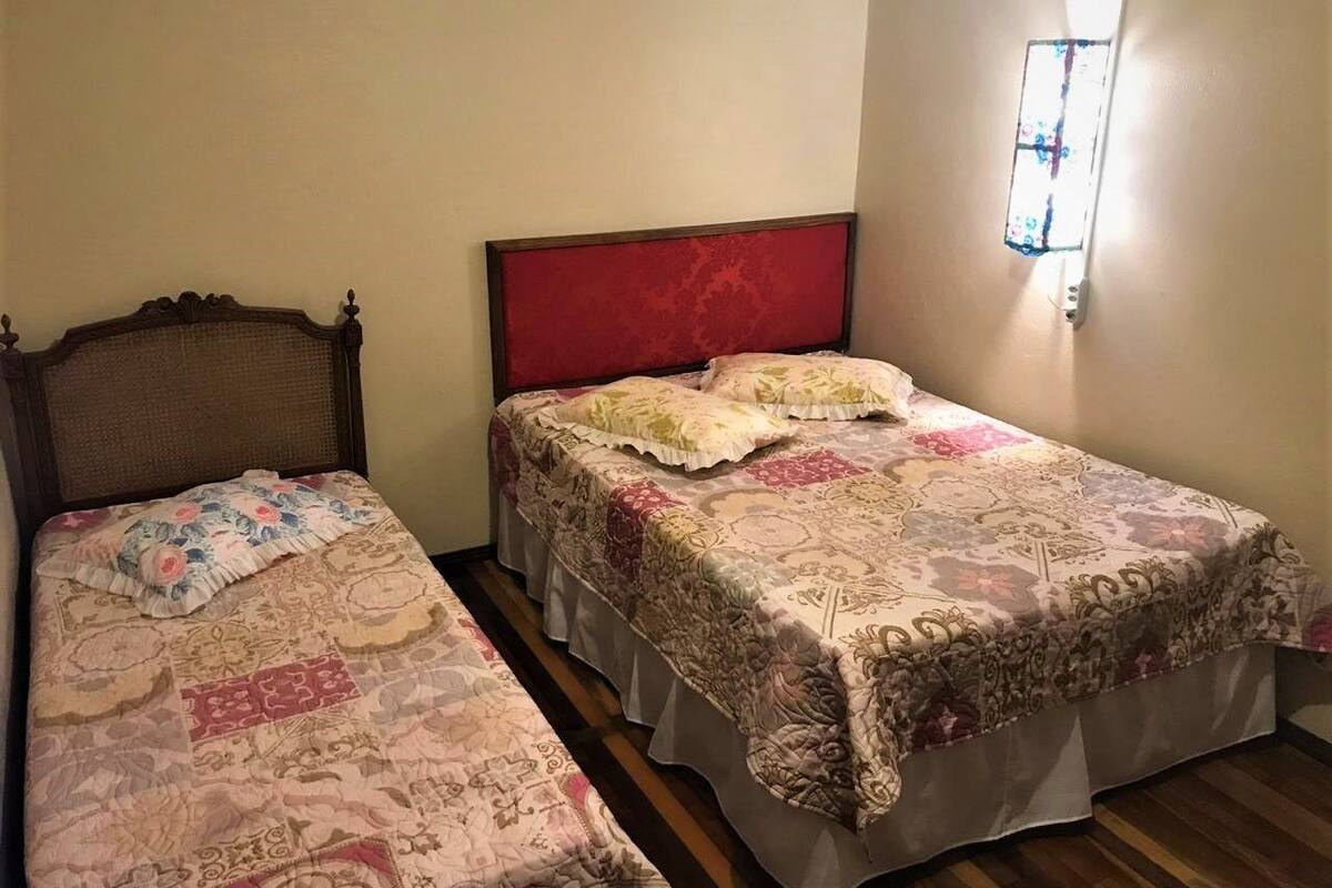 A room with two single beds, each with a patterned bedspread and a headboard.