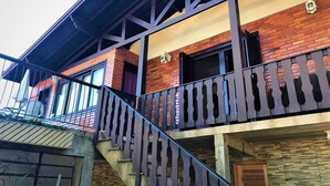A multi-story building with a brick facade, a balcony with a metal railing, and a staircase leading to the upper floors. - Residenciais Gramado House (Gramado)