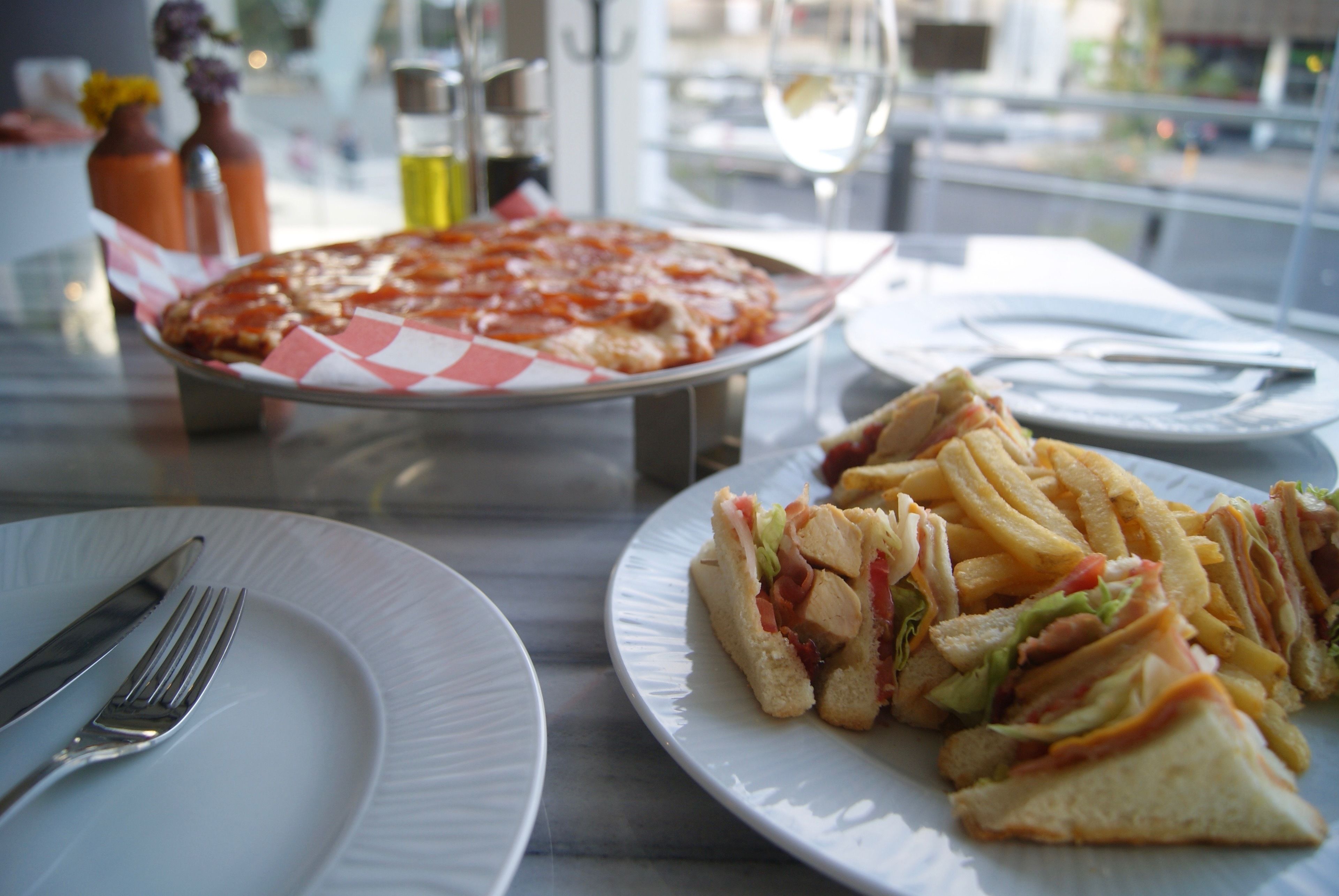 Een eettafel met pizza, belegde broodjes en friet.