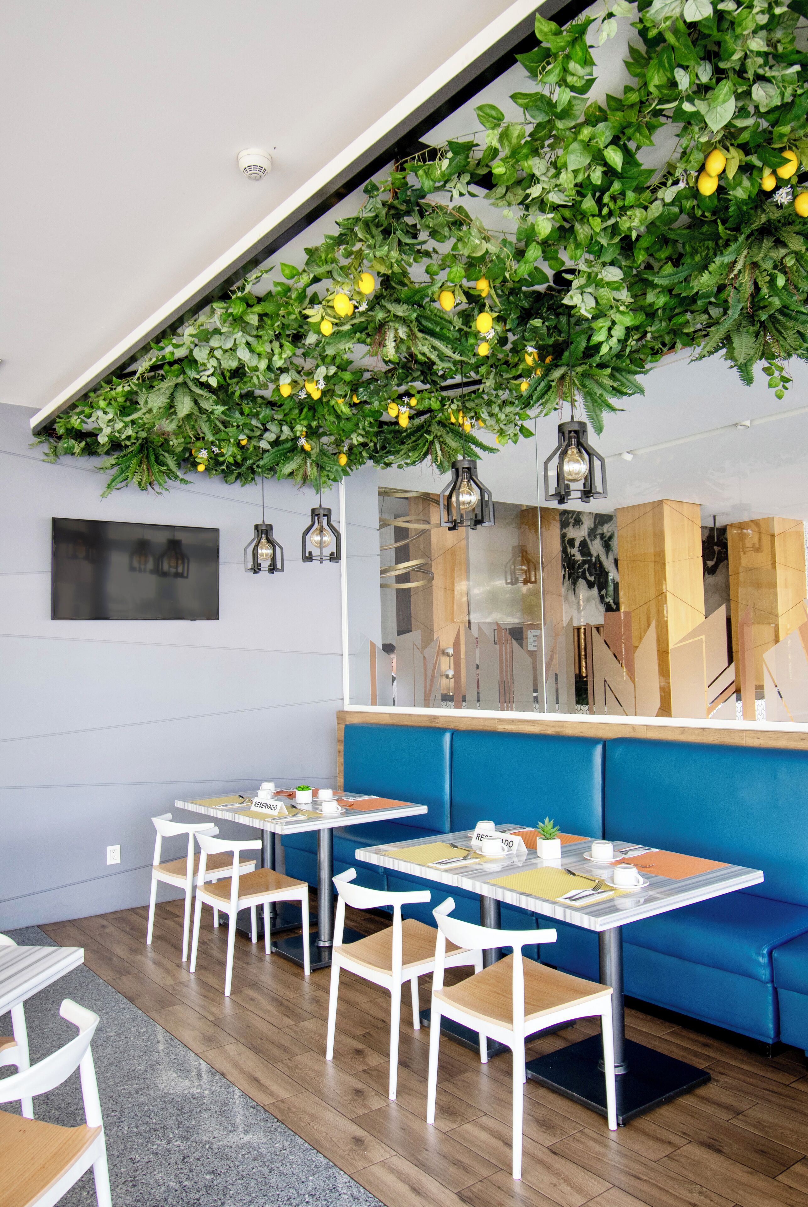 Un café moderno con un sofá azul, mesas y sillas de madera.