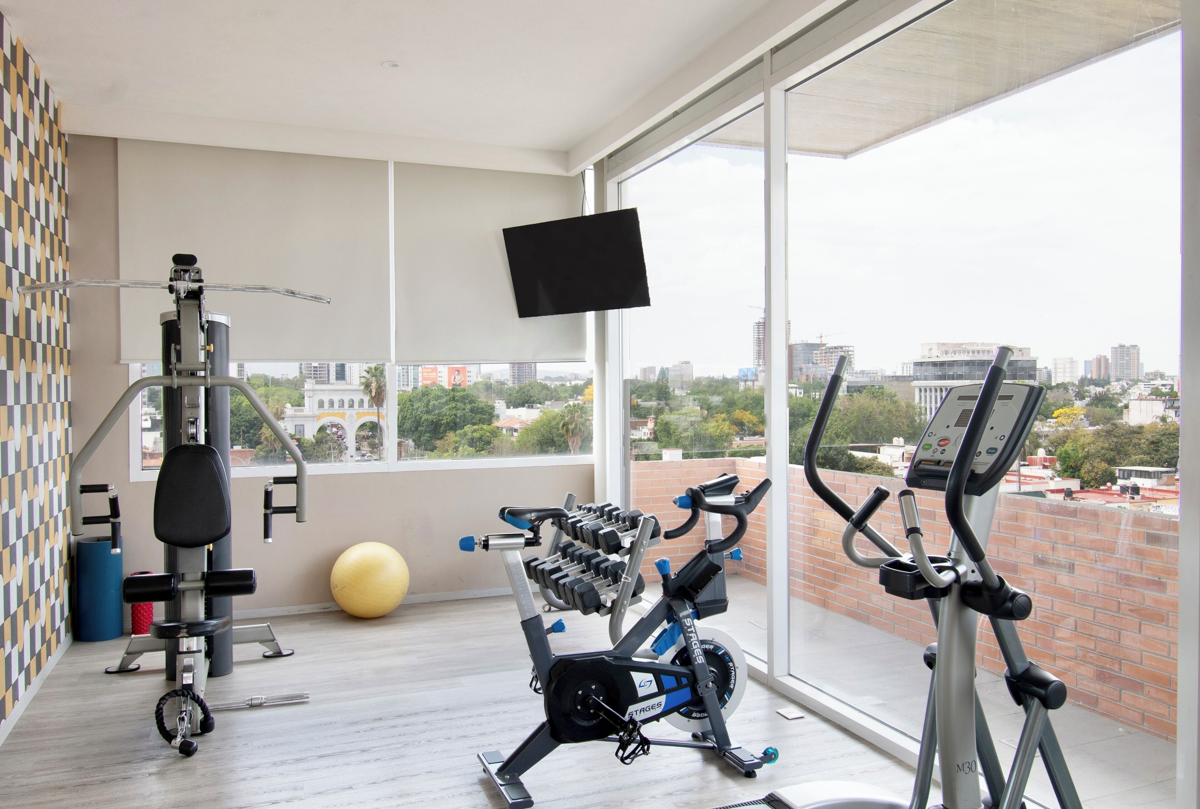 A modern gym with exercise equipment, a large exercise ball, and a TV on a wall.