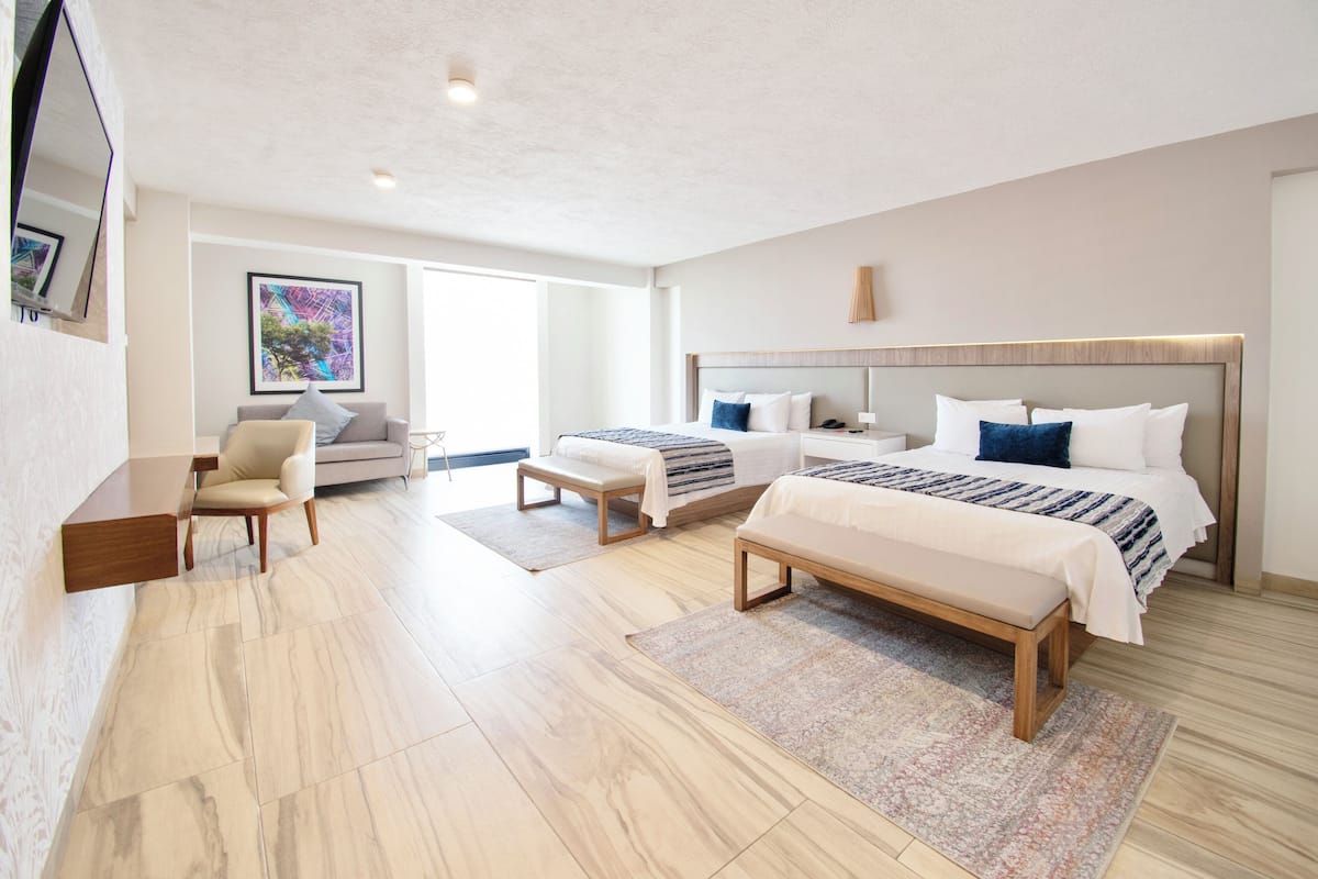 Una habitación de hotel moderna con dos camas, un sofá, un escritorio y un ventanal grande.