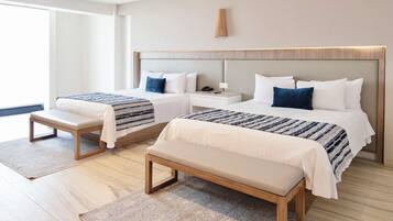 A hotel room with two beds, a bench, a bedside table, and a large window.