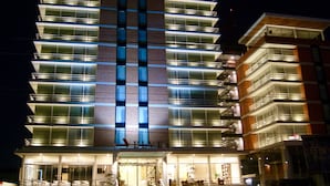 A multi-story hotel with a modern design, featuring a prominent entrance with steps and a glass facade. - Hotel Velvet Plaza (Guadalajara)