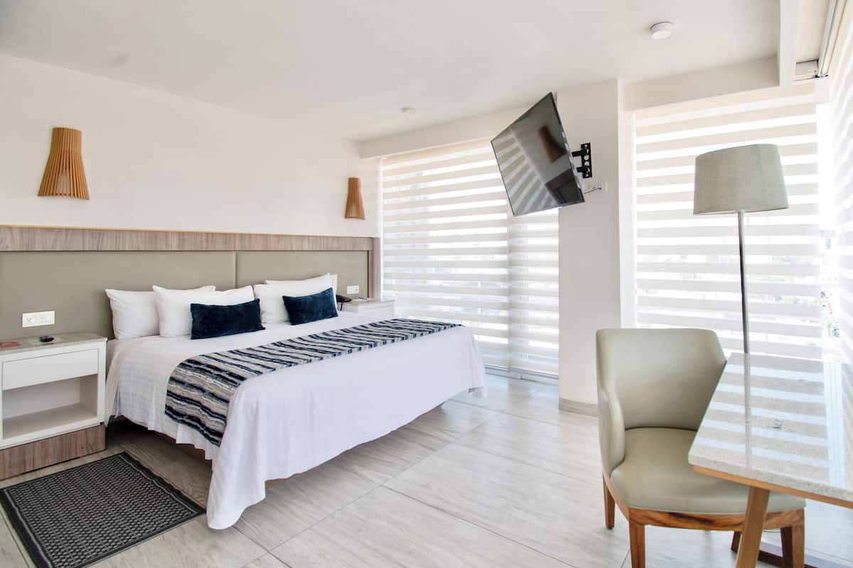 Una habitación de hotel moderna con una cama grande, mesitas de noche, un escritorio y una silla.