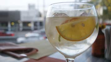 A glass of water with an orange slice on a table with a red napkin and a brown bag.