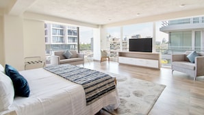 A modern bedroom with a large bed, a TV, and a view of the city. - Hotel Velvet Plaza (Guadalajara)