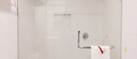 Une salle de bain moderne avec une douche à parois de verre, des toilettes blanches et un porte-serviettes avec une serviette.